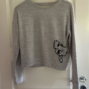 Tunn Hollister tröja - En jättefin tunn hollister tröja i ljusgrå. Tröjan är öppen på ryggen som man kan se på sista bilden. Väldigt bra skick! Tröjan har en liten koala längst ner i det vänstra hörnet av tröjan! Älskar denna tröja men kommer tyvärr inte längre till användning💗