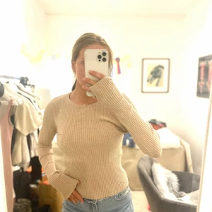 Beige figursydd tröja  - Figursydd, något längre ärmar med slits. Beige.