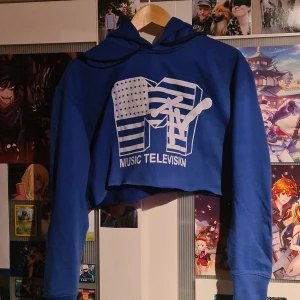 Cropped MTV hoodie - En croppad blå MTV hoodie från second hand. Trycket är lite slitet och luvan är liten. Vet inte om det är något speciellt märke för plgget har ingen lapp.