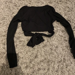 Svart långärmad tröja med knytning bak - Super fin svart tröja med v ringning och var knytning baktill. Aldrig använd