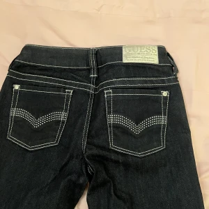 Guess lågmidjade jeans  - Säljer ett par lågmidjade guess jeans i en mörkblå tvätt, de är använda sparsamt och i gott skick. Storlek 27 (passar xs-s, passar längden 167 cm)