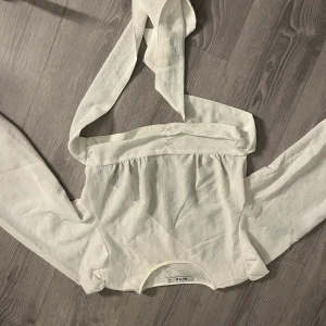 Långärmad blus med öppen rygg - Från NA-KD en vit blus med öppen dig och knytning med långa ärmar. Endast använt en gång