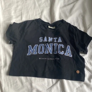 Svart lite kortare t-shirt med tryck - Jag säljer denna för att den är för kort. Använd några få gånger. Strl 134/140