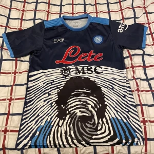 Napoli fotbollströja stl M men passar S - Säljer en Napoli fotbollströja den är aldrig använd den är stl M men passar på S, Med maradona på ryggen den är ganska sällsynt.