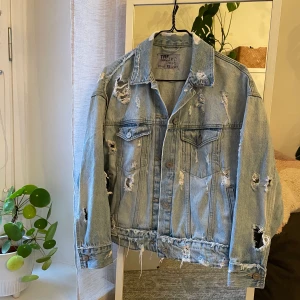 Jeansjacka strl XS - Jeansjacka med slitningar i en oversized modell. Jag är en S/M i vanliga fall men den här passar bra i XS. I gott skick. 