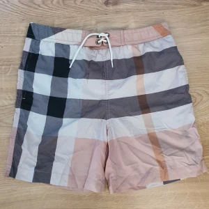 Burberry badbyxa - Burberry badbyxa i Nova check mönster i fina färger. Storlek 140 cm, 10 år. Mycket bra skick, inga fläckar eller märken, dock har resåret i midjan tappat elasticitet. 