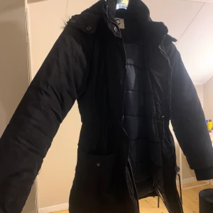 Vinterjacka  - Vinterjacka. Storlek 158. Köpt för två år sedan och säljer pga att jag ej använder längre. Sytt ett hål vid sidan om (se bild) men inget man lägger märke till. 