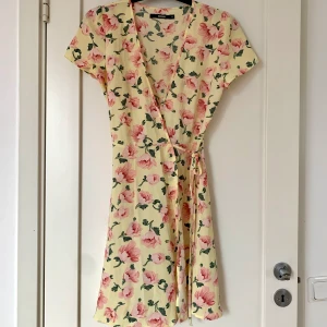 Blommig klänning - Säljer min ljusgula blommiga omlottklänningen som bara använts ett fåtal gånger. Köparen står för frakt