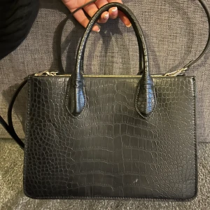 Svart väska i croc  - Fin och rymlig svart väska från hm i croc mönster, väskan har både handtag samt axelrem. Den har även fack inuti. Väskan har knappt använts och har ej skador/defekter. 