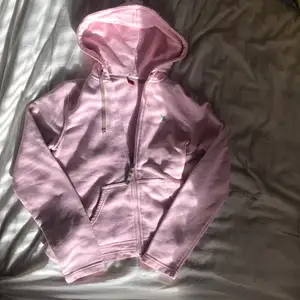 En ljus rosa zip up med en grön fjäril på vänstra bröst. Inga fläckar och helt nopper fri. 