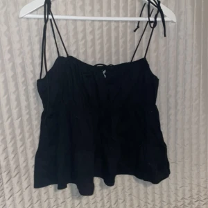 Svart topp i storlek S - Super fina detaljer med en liten knytning på framsidan och på axelbanden, väldigt strechig så den skulle kunna passa en M🥰🥰