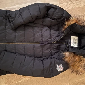 Odd Molly Dunjacka  - Svart dunjacka från Odd Molly. Fint skick och endast använd ett fåtal gånger. Avtagbar luva med fuskpäls. Rök- och djurfritt hem. Stl M/2. 