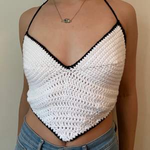 beautiful handmade top in a heart shape with an open back. perfect to wear by itself in the summer, or as a layering piece over another shirt in the winter. crocheted with 100% acrylic yarn. White heart with a black border and straps. 