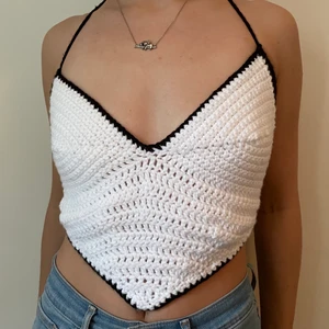 handmade crocheted heart top - beautiful handmade top in a heart shape with an open back. perfect to wear by itself in the summer, or as a layering piece over another shirt in the winter. crocheted with 100% acrylic yarn. White heart with a black border and straps. 