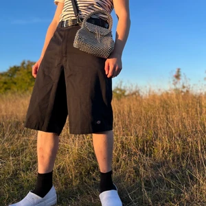 Svarta Dickies shorts 33/M - Coola och klassiska Dickies shorts passar till det mesta snyggast till ett par långa vita strumpor för o få den ”cholo stilen”. Finns en liten fläck under loggan på baksidan knappt synlig annars inget annat. Långa i längden. Midja: 88cm. Benbredd:34cm 