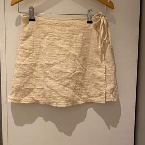 Kräm vit kjol från zara med knytning på sidan. ( har även en knapp) Materialet är lite ådrat. Storlek S  Kjolen är använd ett fåtal gånger därav i fint skick. 