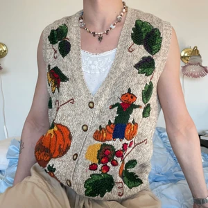 Oversized stickad väst beige pumpor växt - Beige oversized vintage stickad väst med det finaste motivet föreställande pumpor, en fågelskrämma, grönsaker och växter 🫑❣️ Den skönaste västen du kan hitta och dessutom är den handstickad! Färgerna går så bra tillsammans och passar så bra nu till våren med en långärmad under och till sommaren med ett linne + ett par linnebyxor! :D <3