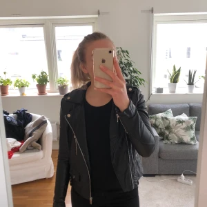 Skinnjacka - Svart skinnjacka (ej äkta skinn, utan polyester) från bikbok. Inköpt ca 2015, sparsamt använd och har legat i garderoben senaste åren. Inga defekter förutom att öglan för att hänga upp på krok har gått av, men detta kan lagas