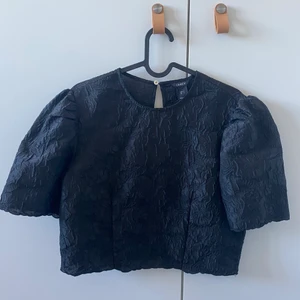 Topp i Jacquard - Svart festtopp i jacquardmönster med blommor. Perfekt till sommarens fester med en kjol eller ett par byxor med lite färg. 🪴 sparsamt använd, från Lindex.