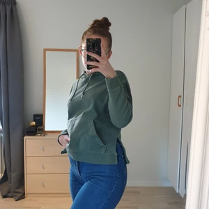 Grön huvtröja tjocktröja med slit - Grön tjocktröja med slits på båda sidorna. Använd fåtal gånger. S men passar även M