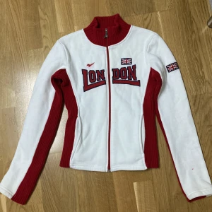 Nas London Zip-up Kofta - Supersnygg kofta i väldigt bra skick. Nästan exakt som den Bella Hadid hade på sig ett tag sen i blå/vita colorway. Den har tyvärr en liten fläck på framsidan, jag köpte den secondhand och har aldrig använt så vet inte om den går bort men den syns knappt.