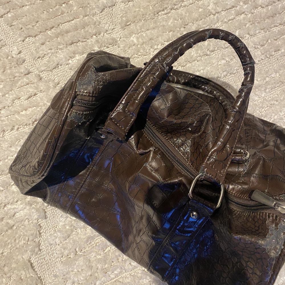 En jättefin, brun medelstor väska. Har några mindre slitningar uppe vid dragkedjan som syns på andra bilden men inget jag tycker man lägger märke till. Skriv gärna om ni har frågor!. Väskor.