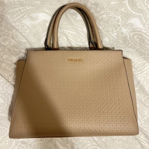 Väska - Handväska från VEZZANO i mycket fint skick, säljer då den inte kommer till användning längre. Använd fåtal gånger. Medelstor (får plats med en 13 tums laptop i om man vill ha den till skolan)