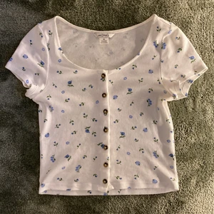 Blommig t-shirt - En super söt t-shirt med blå blommor på! 💕 Är i storlek XS men passar även S, då materialet är stretchigt. Tröjan är ifrån Monki och är inte mycket använd och i bra skick! 🥰
