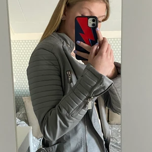 Grå skinnjacka från chiquelle! - Säljer nu min gråa skinnjacka från Chiquelle då den inte kommer till användning längre. Köptes sommaren 2019 och finns inte kvar på Chiquelles hemsida längre. Storlek 40 och sitter lite tajt på mig som vanligtvis har storlek S. Jackan är väl använd och har lite slitningar på ena armen (se bild tre). Kostade runt 400kr mitt pris är 150kr+ frakt!
