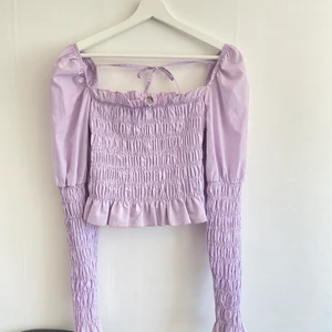 Lila smocktopp - Pastellila tröja med smock från GinaTricot. Bak i ryggen finns två band som t.ex knyts ihop till en rosett (se bild två). Axlarna är puffiga men ärmarna är i smock. Tröjan är knappt använd och i strl S. Skriv för fler bilder!