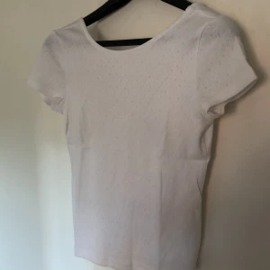 Vit tröja - Supersöt vit tröja med lite djupare rygg. Tyget är väldigt skönt och har även ett litet mönster av hål som syns bäst på sista bilen. Den är nästan helt oanvänd. Storlek s. Den kostar 50 kr +frakt som betalats av köpearen 
