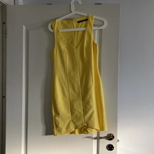 Sommarklänning  - Gul sommarklänning. V-ringad. Knäppning med dragkedja baktill. 