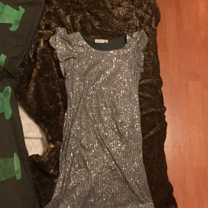 Glittrig klänning  - Glittrig klänning med silverfärgade paljetter säljer p.g.a inte gillar den och är snart för liten, pris kan diskuteras och den har fladdriga armar har ändast använt 3 gånger🤍