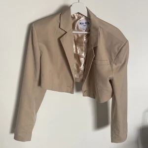 Kort kavaj  - Snygg kort beige kavaj från NA-KD. Storlek 42 men använd den sparsamt som oversiz.