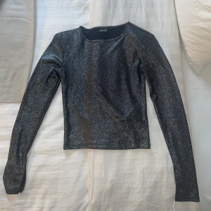 Glittrig Tröja - Gråglittrig långärmad tröja med axelvadd (går att sprätta bort om man skulle vilja). Från Ginatricot. Storlek Xs. Bra skick! Använd endast en gång. 