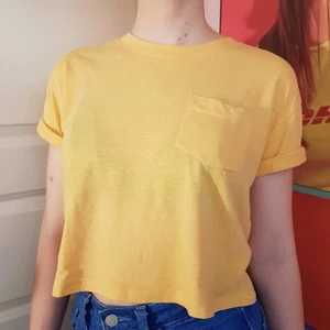 Gul croptop - Gul croppad tshirt med uppvikta ärmar och en liten ficka. Jättemjuk och skön!