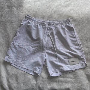 Calvin Klein Badbyxor - Ett par Calvin badbyxor storlek M köpta från Zalando. Fickor fram och en bak. Ej genomskinliga, matt i tyget.