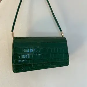Vintage looking mörkgrön väska med guld detaljer. Den perfekta lilla väskan nu till hösten
