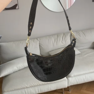 Onesize - Svart lackerad väska med guldiga detaljer 