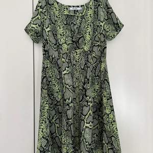 Grön klänning med ormskinns print. Går till strax över knäna. Aldrig använd.