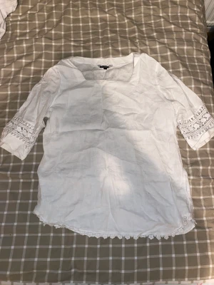 Vitt kort klänning  - Vit kort , kvartärmad klänning med Blom mönster längst ner på armarna 