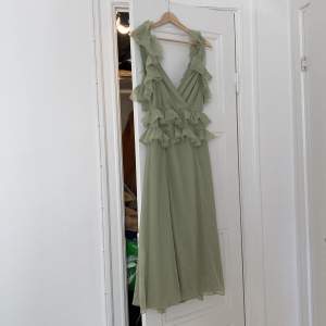 Superfin salviagrön midi-klänning från ASOS Design. Fin volang och knytning i ryggen! Storlek 38.  Aldrig använd. 