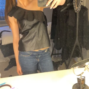 One shoulder topp - Jätte snygg one shulder topp i skinn imitation med volanger båda fram och bak. Storlek 38.