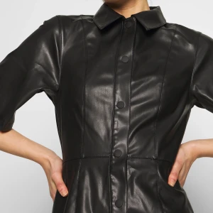 Läderklänning Weekday - Denna supersnygga läderklänning ”Savanna” från Weekday är endast använd fåtal gånger, mest för bildtagning. Använde den som ytterplagg där den var öppen som en väst/rock. Men går såklart utmärkt använda som en knäppt klänning och styla med långärmat under