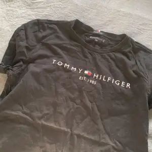 snygg svart t-shirt ifrån Tommy hilfiger herr modell storlek 176. Använd fåtal gången annars extremt fint skick ! Köpare står för frakt 