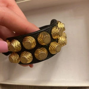 Balenciaga armband - Säljer mitt fina balenciaga armband!! Guldigt med svart skinn. Svin coolt och passar till vardags och fest!! Det är använt men fortfarande bra skick🥰 har inget kvitto men box ingår, garanterat äkta! Köptes på NK 2017 om jag inte minns fel🤩