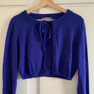 Croppad kofta - jättesöt, mörklila, croppad kofta som man knyter med små hjärtan på! den var min mammas i början av 00-talet och har aldrig fått mer använding av den 💜 står att den är M men passar mer en S, kanske XS <33