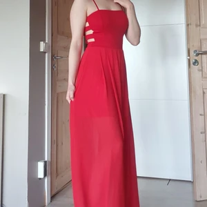 Röd långklänning - Aldrig använd, endast testad! Köptes på marknad i Bulgarien för många år sen och har bara hängt i garderoben. Banden är inte avtagbara, det finns ingen lapp som beskriver storlek eller tvättråd. Som referens är jag 170 lång och har vanligen storlek XS/S
