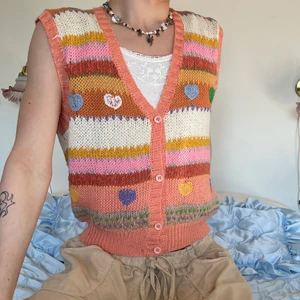 Färgglad stickad väst hjärtan - Färgglad stickad väst i aprikos, lila, rosa, brun, blå, lila, gul, orange och grön med hjärtan 🧡💚💜 Inte bara sitter den bra utan prassar med allt iom alla färgerna! Så snygg med ett vitt ribbat linne eller långärmad under och ett par bruna manchesterbyxor! :D