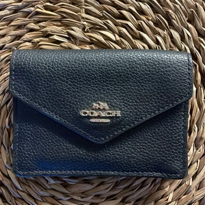 Coach plånbok - Den är fräsch och i bra skick! Den är en mindre plånbok som får plats med kort, mynt, sedlar samt har en nyckelring i sig. Den är svart med gulddetaljer. 